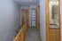 Inviting hallway with carpeted flooring, featuring a bathroom entrance with modern sink and shelving for organized storage.