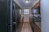 Modern galley kitchen with sleek black appliances, warm wood cabinetry, and ample counter space, offering a cozy culinary experience.