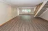 Spacious living area with elegant hardwood floors and modern staircase, bathed in natural light from large windows.