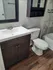 Modern bathroom with elegant dark wood vanity, sleek white countertop, and stylish tile accents.