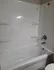 Pristine white bathtub with modern fixtures and built-in shelving, ideal for a relaxing soak.