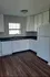 Charming kitchen with elegant white cabinetry, modern appliances, and sleek countertops, complemented by rich hardwood flooring and natural light from a sunlit window.