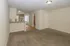 Inviting open-plan living area with plush carpeting, modern kitchen, and natural light.