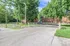 Charming brick apartment nestled in lush greenery with inviting driveway and serene surroundings.