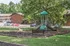 Charming apartment complex with a vibrant playground surrounded by lush greenery, offering an inviting and family-friendly environment.