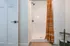 Bright bathroom with modern shower and stylish orange striped curtain, offering a refreshing space.