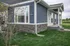 Charming blue house exterior with modern stone accents and lush green lawn.