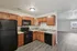 Modern kitchen with sleek black appliances, warm wooden cabinetry, and elegant tile backsplash in a sunlit apartment.