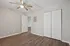Bright and inviting bedroom with elegant wood flooring, sleek ceiling fan, and double-door closet.
