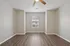 Bright and inviting room with elegant wood flooring, modern ceiling fan, and a central window offering a cozy view.