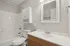 Modern bathroom featuring sleek white fixtures, a stylish vanity with storage, and elegant neutral tones, offering a serene retreat.