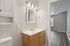 Bright and inviting bathroom with elegant lighting, pristine vanity, and modern flooring leading into a spacious room.