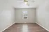 Bright room with sleek wooden flooring, neutral walls, and a central ceiling fan, featuring a sunlit window with modern blinds.