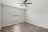 Bright, freshly painted room with elegant wood flooring and a modern ceiling fan, perfect for customization.