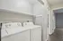 Modern laundry room with sleek washer and dryer set, complemented by stylish cabinetry and a bright, airy hallway.