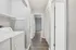 Bright hallway with modern laminate flooring, featuring a convenient in-unit laundry area and sleek white doors leading to spacious rooms.
