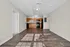 Modern open-concept living space with wood floors and a sleek kitchen featuring wooden cabinets and black appliances.
