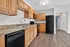 Charming kitchen with modern black appliances, elegant wood cabinetry, and a sleek countertop under a bright ceiling light.