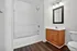 Sleek bathroom with modern fixtures, inviting bathtub, elegant wooden vanity, and contemporary lighting.