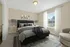 Bright and cozy bedroom featuring a plush bed, modern nightstands, and a large window with elegant curtains, perfect for relaxation.