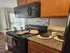 Cozy kitchen with modern appliances, featuring a sleek black stove, microwave, and stylish backsplash, complemented by wooden cabinets and natural light.