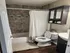 Elegant bathroom featuring a modern white and gray tile design, stylish wooded vanity, and cozy shower setup with a chic cabinet for storage.