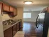 Contemporary kitchen with sleek countertops, modern appliances, and warm wooden cabinetry leading to a bright living area.