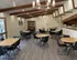 Elegant communal dining area with modern wooden tables, sleek black chairs, and chic chandeliers creating a warm and inviting atmosphere.