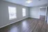 Bright and spacious living area with elegant wood flooring, large windows offering natural light, and a modern ceiling fixture.