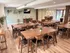 Chic communal dining area featuring modern wooden tables and chairs, adorned with lush greenery accents and stylish decor.