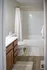 Bright and elegant bathroom featuring a white countertop and vanity, with a cozy shower enclosed by a stylish curtain.