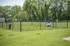 Expansive fenced bark park surrounded by lush greenery, perfect for pets to enjoy outdoor playtime.