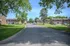 Charming residential complex with lush greenery, featuring brick buildings and spacious parking, offering serene suburban living.