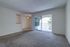 Royal Breeze Apartments Inc, interior, carpeted living room, sliding glass door with blinds to balcony, entrace to dining room, ceiling fan, pass-through opening