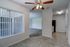 Royal Breeze Apartments Inc, interior, tiled dining room and kitchen, large window with blinds, ceiling fan, carpeted living room, black refrigerator,