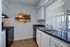 Royal Breeze Apartments Inc, interior, kitchen, wood floor, black appliances, dishwasher, stove/oven, white cabinets, large window with blinds over sink