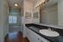 Royal Breeze Apartments Inc, interior, bathroom, spacious dark counter, large mirror, sink, white cabinets, wood floor, entry to carpeted room with window and blinds, closets