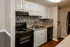 The Avenue Apartments, interior, kitchen, white cabinets, wood floor, black appliances, stove/oven, dishwasher, refrigerator, white stacked washer dryer in laundry nook.