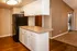 The Avenue Apartments, interior, kitchen, wood floor, breakfast bar counter, white cabinets, black refrigerator, pantry, carpeted living room, sliding glass doors.
