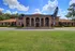 The Rio Apartments, exterior, brick building, high archways, red shudders, large grass area, driveway, trees, blue skies