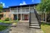The Rio Apartments, exterior, two story brick building, stairs to second level balconies, red door, trees, grass, walkway