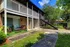 The Rio Apartments, exterior, walk ways, grass, two story brick buildings, stairs to second level, trees, lawn furniture on porch by sliding glass door