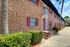 The Rio Apartments, exterior, red door, brick buildings, palm trees, bushes, red shudders, small balcony