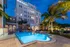 Elegant apartment building at dusk with a glowing pool and palm trees, offering luxurious resort-style living.