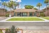 Charming brick leasing office with inviting teal accents, set against a backdrop of lush palm trees and vibrant greenery.