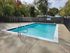 Charming outdoor pool surrounded by lush greenery and secure fencing, perfect for relaxation.