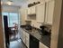Inviting kitchen with white cabinets and sleek countertops leading to a bright dining area with natural light.