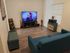Inviting living room featuring a sleek flat-screen TV, stylish teal sofa, and charming wooden decor.