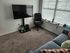 Inviting living room corner featuring a wall-mounted TV, comfortable office chair, and a stylish sofa.
