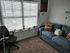 Inviting home office with a plush blue sofa and a comfortable chair by a large window.